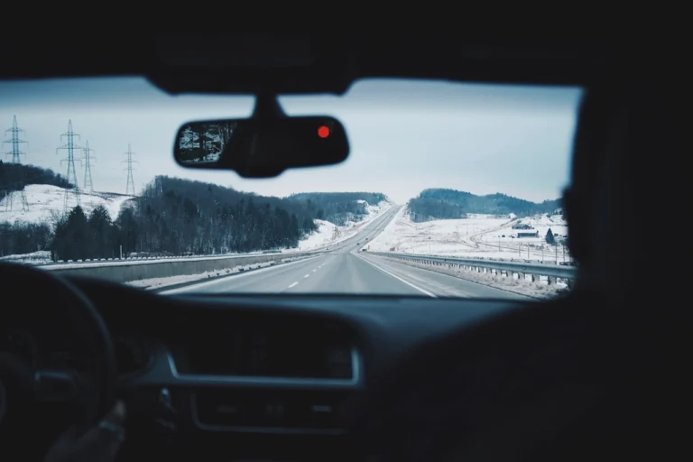 Autostrada innevata vista dal parabrezza, con lo specchietto retrovisore dove si monta una dash cam